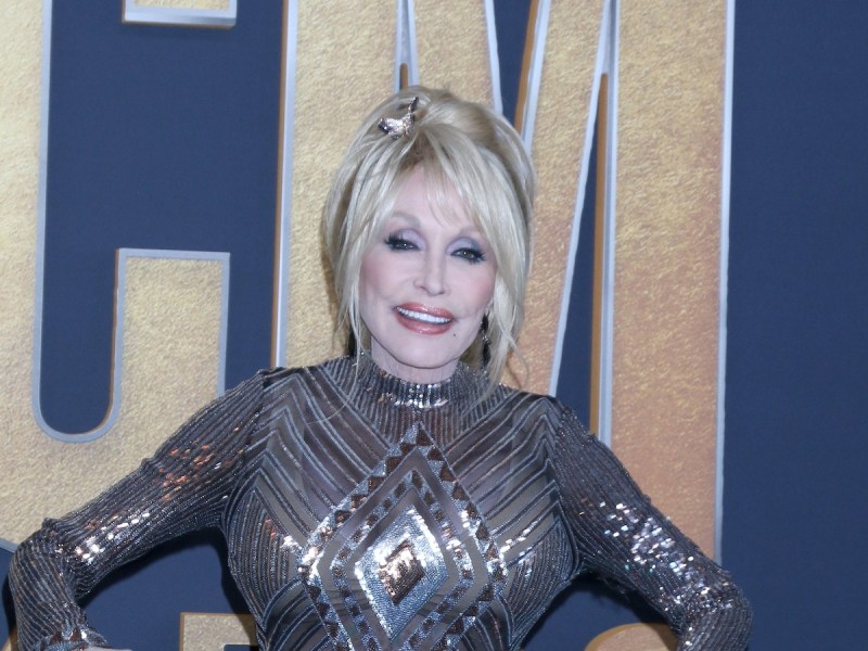 Dolly Parton smiling in a silver and gold dress