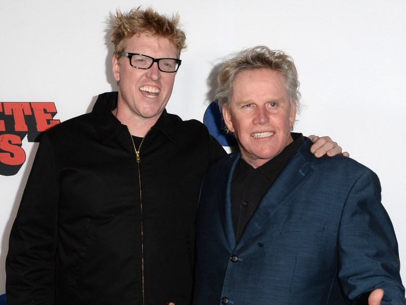 Gary Busey (R) in navy blue jacket standing next to Jake Busey, who is wearing a black jacket