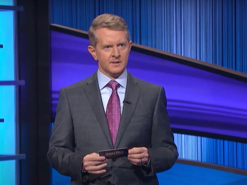 screenshot of Ken Jennings hosting the Tournament of Champions in a gray suit
