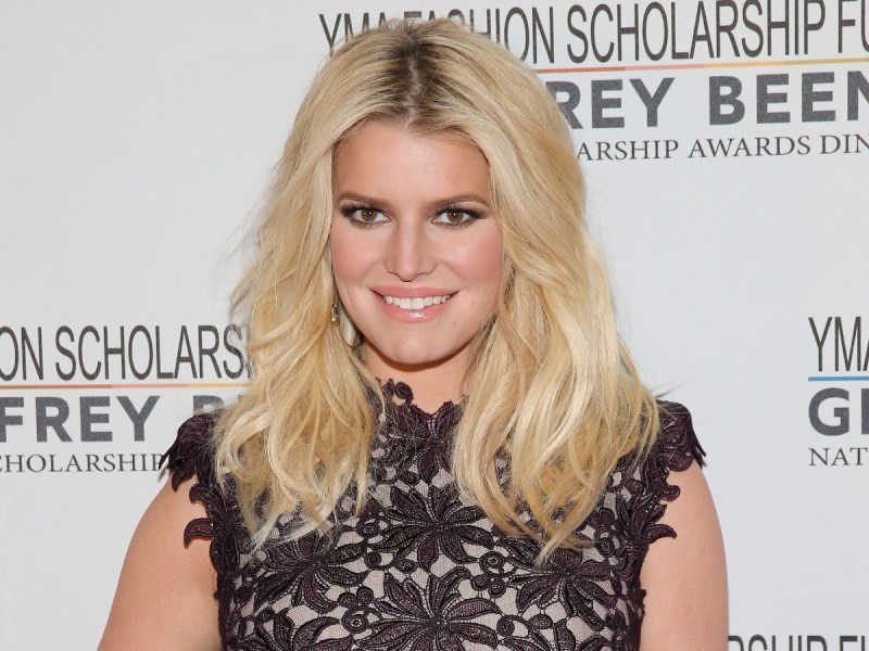 Jessica Simpson smiles in black lace dress against white backdrop