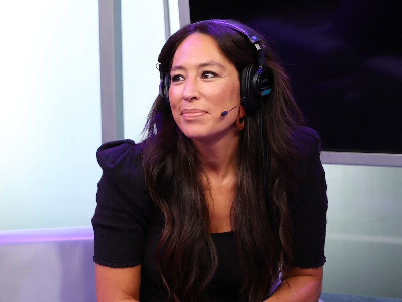 Joanna Gaines smiling with a headset on in a black blouse on a SiriusXM interview