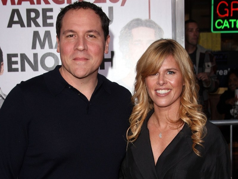 Jon Favreau (L) and Joya Tillem smiling in black shirts against white backdrop