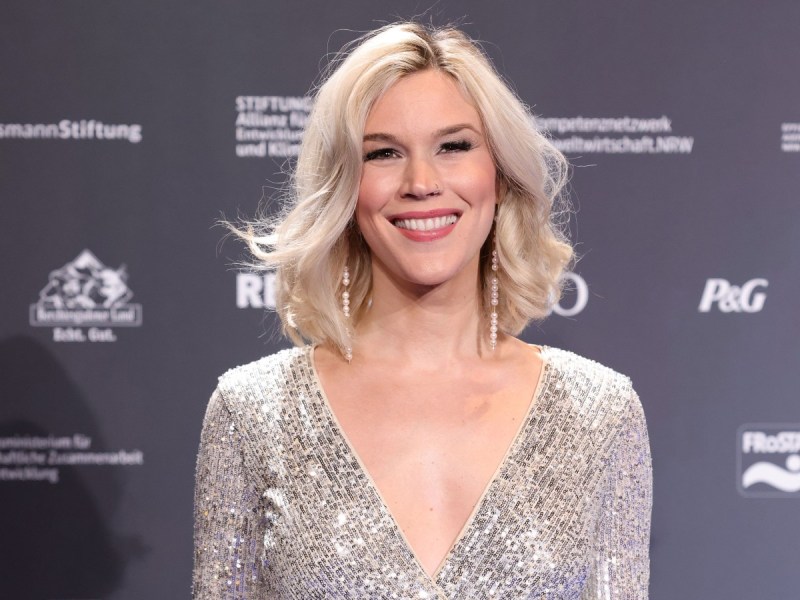 Joss Stone smiles in silver dress against charcoal backdrop