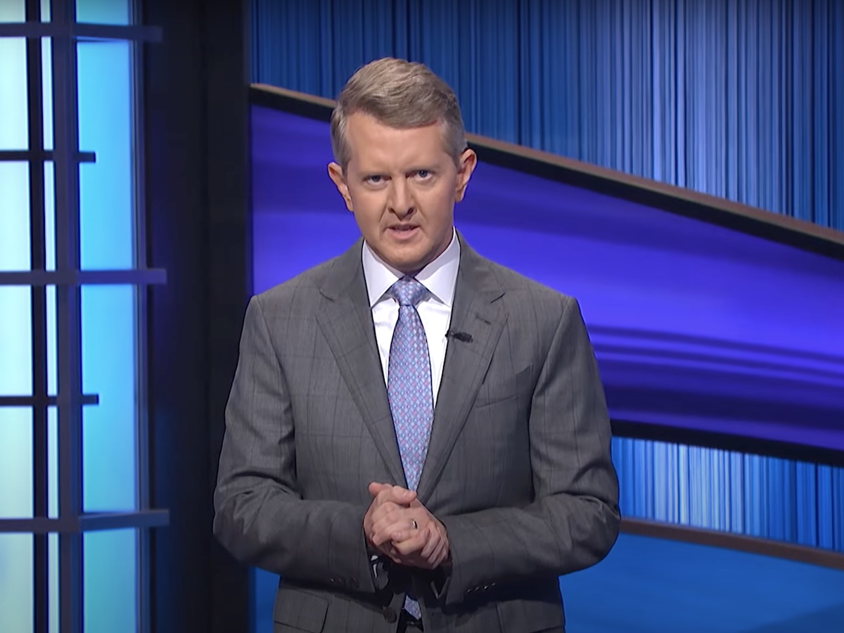 screenshot of Ken Jenning with hands clasped in a grey suit hosting the show