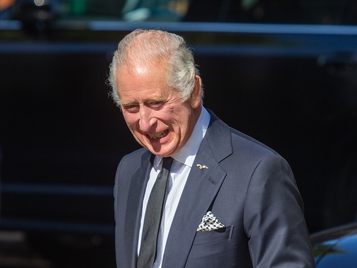 King Charles smiling in a navy suit