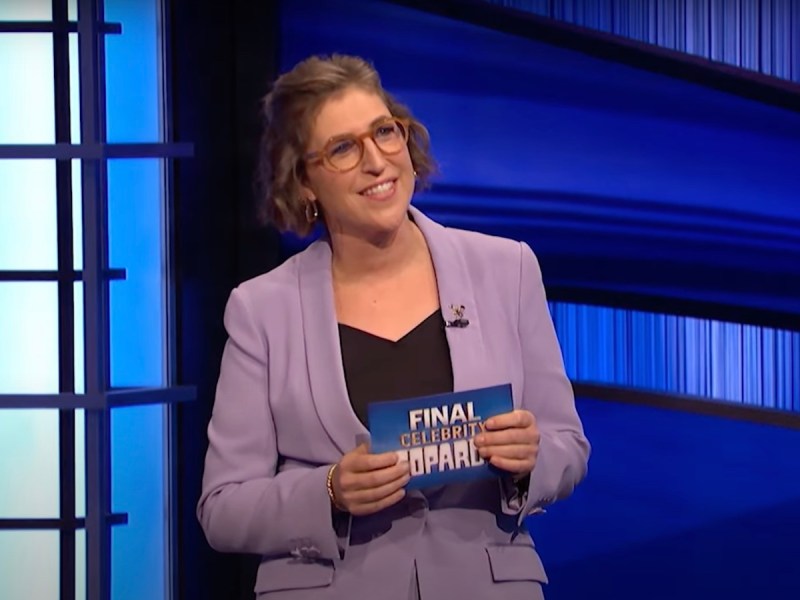 screenshot of Mayim Bialik hosting Celebrity Jeopardy in a light purple outfit