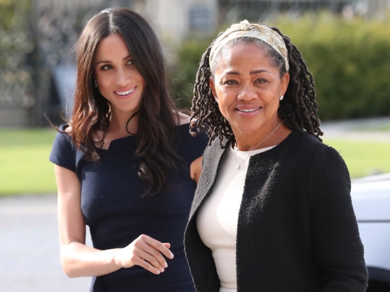 Meghan Markle (L) in black dress walking next to her mother, Doria Ragland, who is wearing a white shirt and black jacket