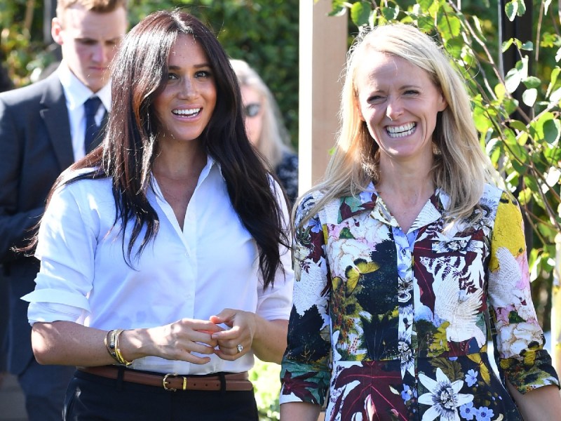 Meghan Markle (L) in white shirt walking next to Kate Stephens, who is wearing a floral jacket