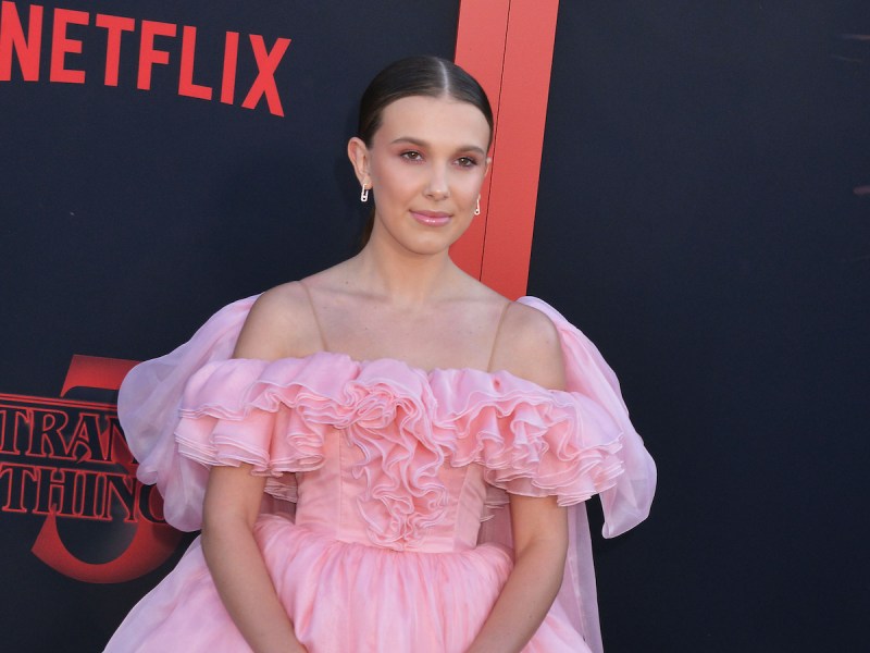 2020 photo of Millie Bobby Brown smiling in a pink dress