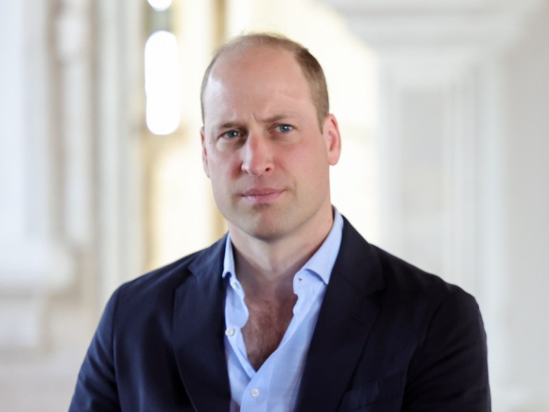 Close up of Prince William with a navy blazer and blue shirt with an unbuttoned collar
