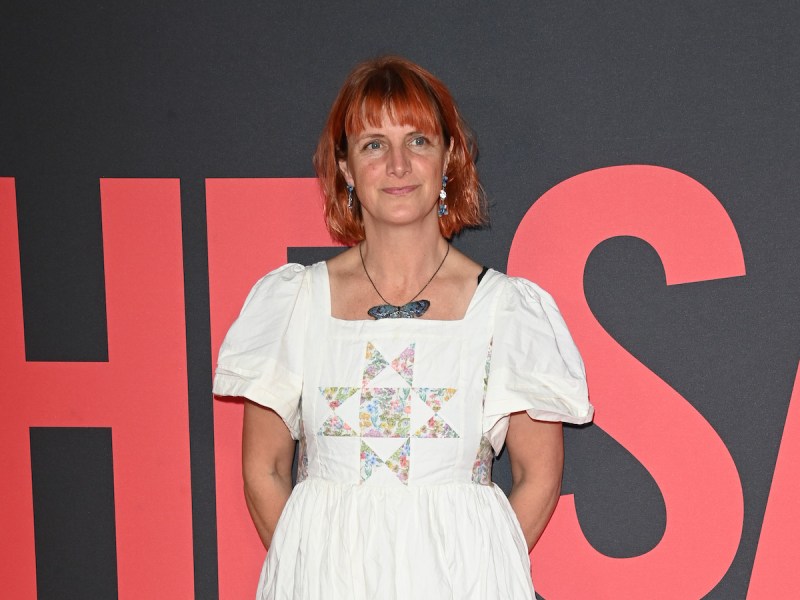 Rebecca Lenkiewicz smiling in a white dress with arms behind her back