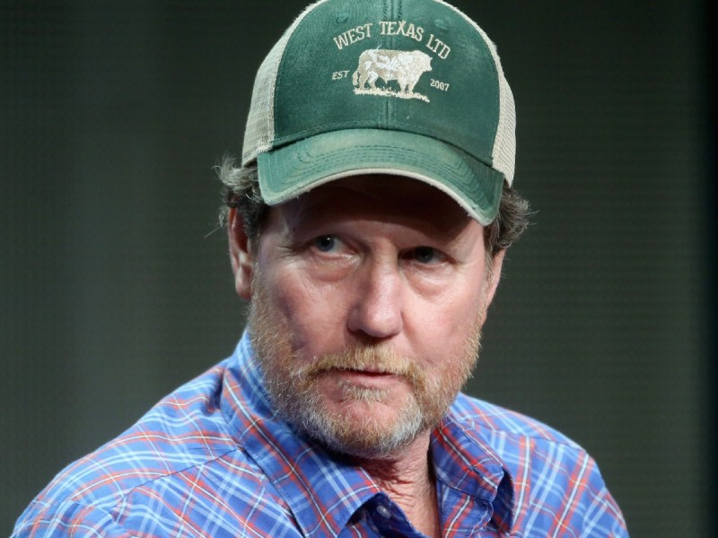 Rooster McConaughey in plaid top and green baseball cap