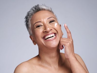 A smiling woman applying face cream