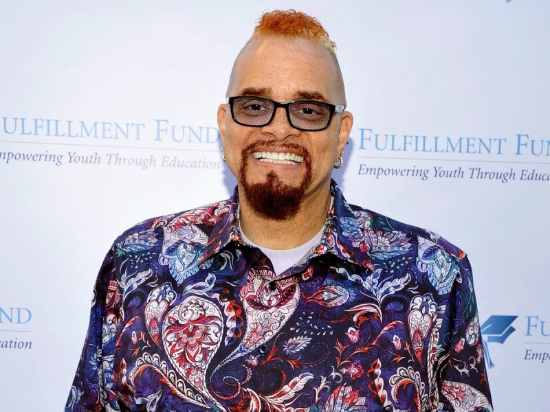 Sinbad smiles in patterned shirt against white backdrop
