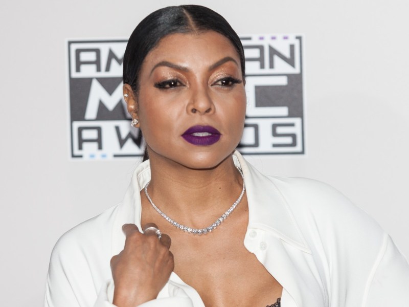 Taraji P. Henson poses in white top with purple lipstick against white backdrop