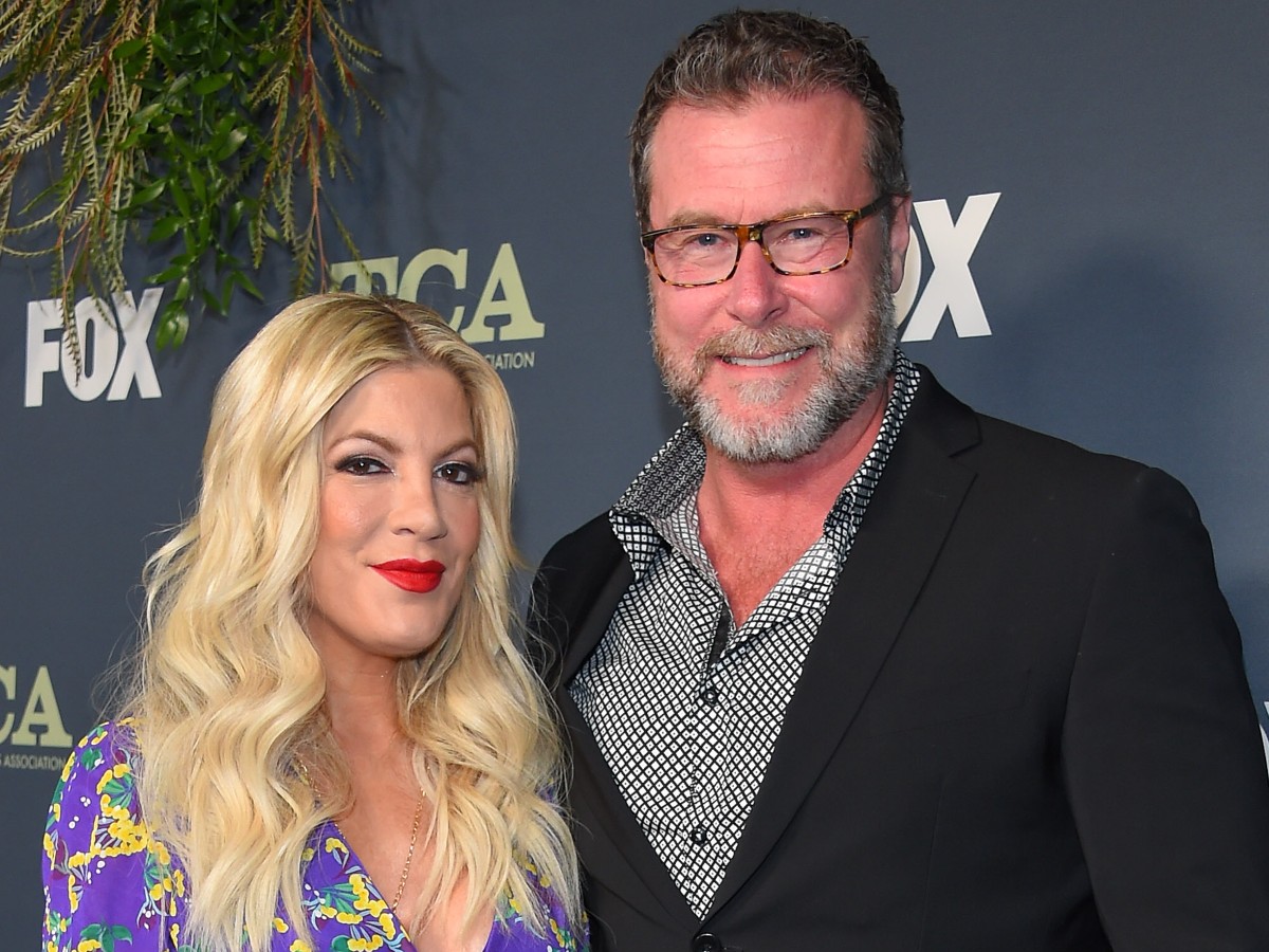 Tori Spelling (L) and Dean McDermott on red carpet against dark gray backdrop