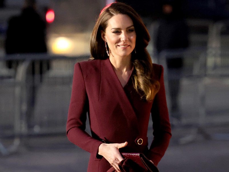 Kate Middleton in a purple coat, smiling before the royal concert at Westminster Abbey