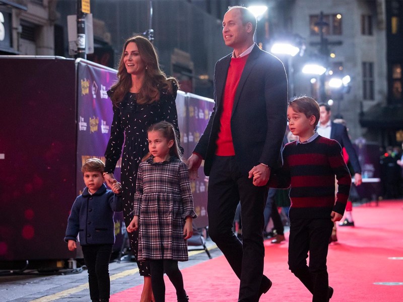 From left to right, Prince Louis, Kate Middleton, Princess Charlotte, Prince William, Prince George all walking together on a red carpet.