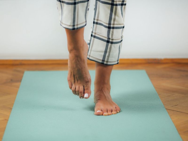 Woman balancing on one foot on a yoga mat