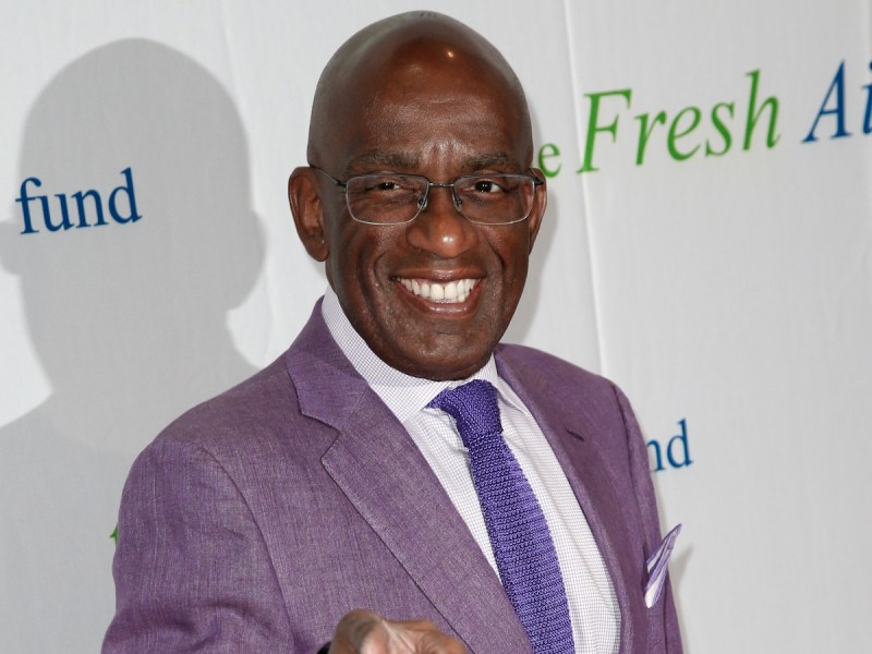 Al Roker smiles in purple suit and matching tie against white backdrop