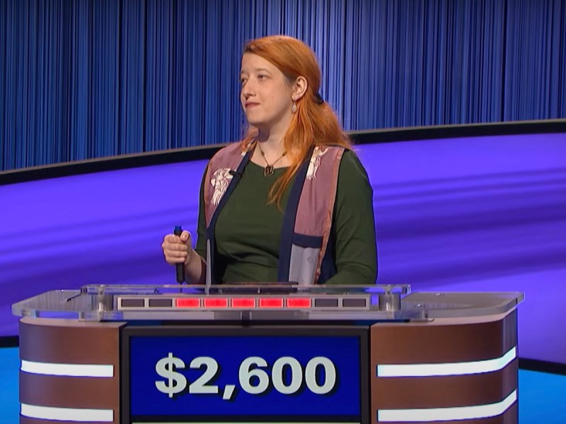 screenshot of A.Z. Madonna buzzing in on Jeopardy in a green top and red vest