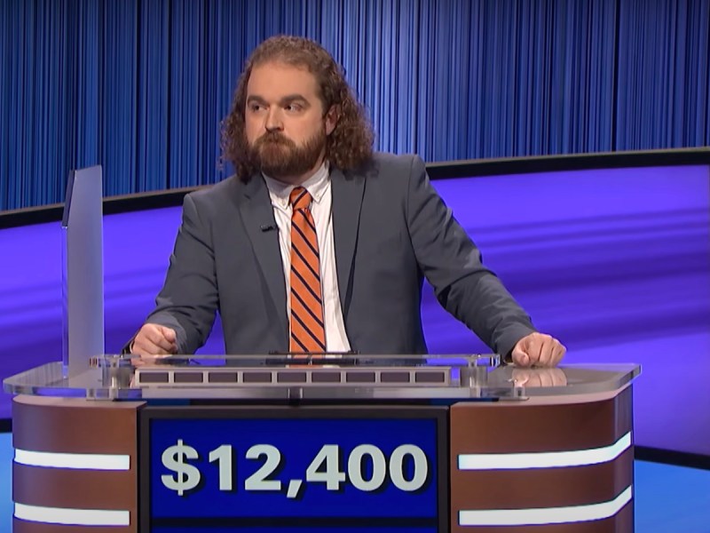 screenshot of Ben Hebert competing on Jeopardy in a blue suit and orange tie