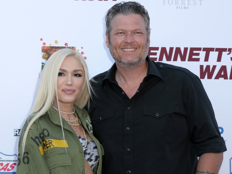 Blake Shelton (R) in black top standing with Gwen Stefani, who is wearing a green jacket