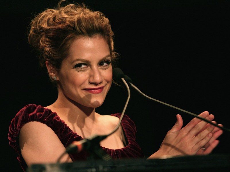 Brittany Murphy smiles and claps hands in red dress