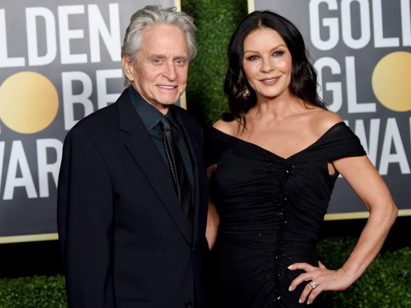 Catherine Zeta-Jones (R) in black gown posing next to Michael Douglas, who is also dressed in all black