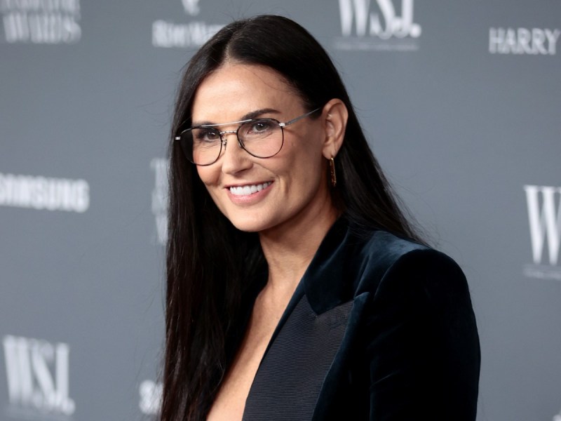 Demi Moore smiles in black blazer against gray backdrop