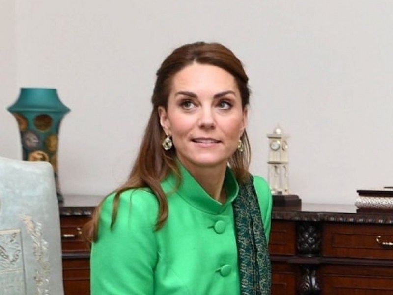 close up of Kate Middleton smiling in a green dress while sitting in an office