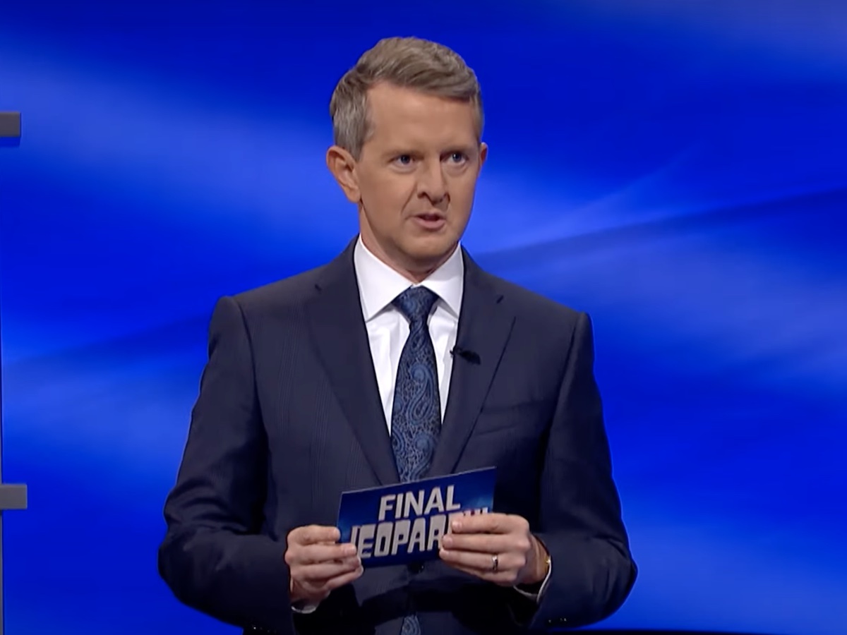 screenshot of Ken Jennings hosting Jeopardy in a navy suit and tie