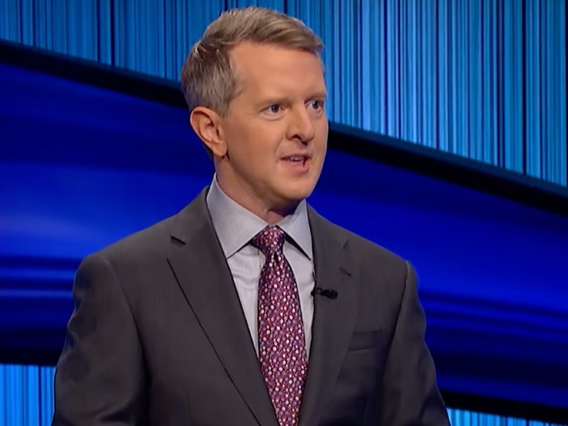 Ken Jennings in suit and purple patterned tie on "Jeopardy!" stage