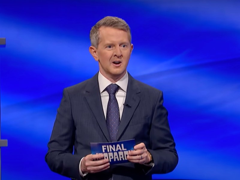 screenshot of Ken Jennings in a navy suit and tie announcing Final Jeopardy
