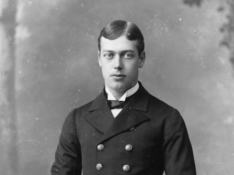 black and white photo of young King George V in a black coat and bowtie and short moussed down flat hair
