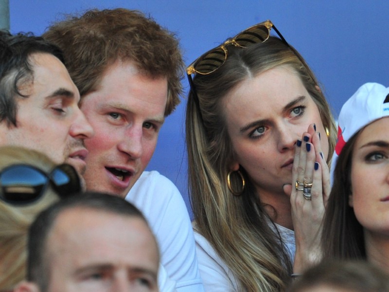 Prince Harry (L) and Cressida Bonas sitting in bleachers talking to each other