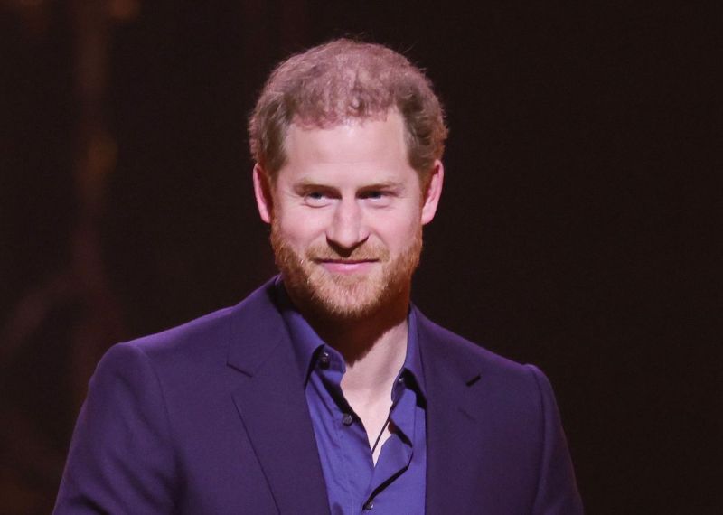 Prince Harry smiling in a purple suit