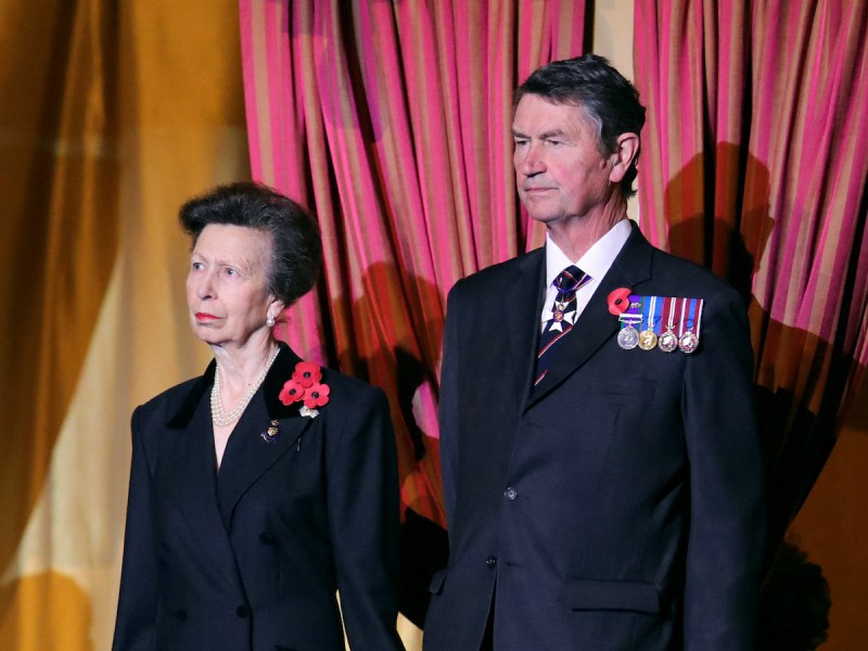 Princess Anne in a black jacket standing in a balcony with husband Sir Timothy Laurence