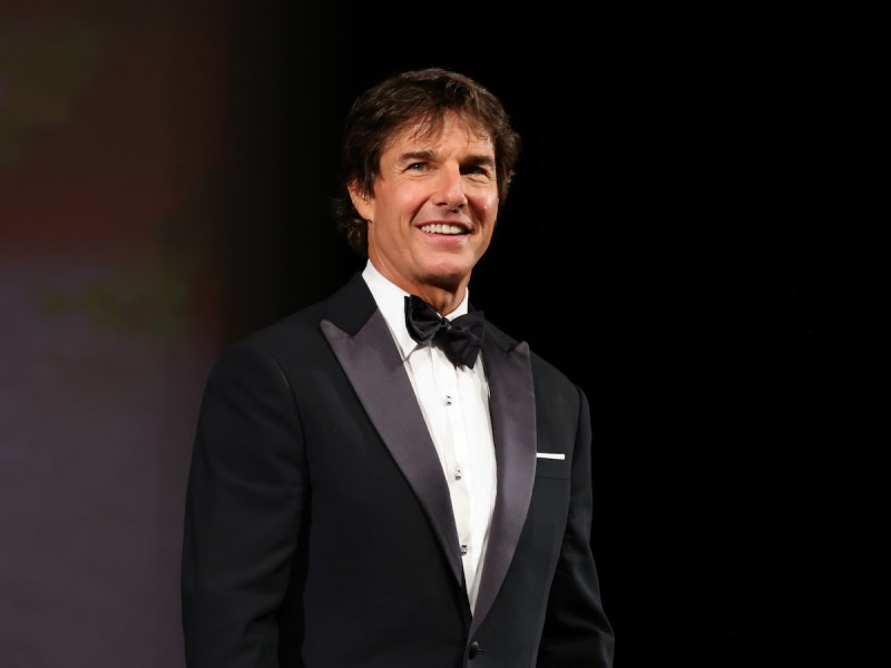 Tom Cruise smiling in a tuxedo on a stage