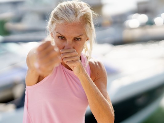 a woman with white hair punches towards the camera