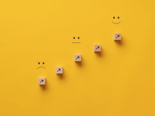 Diagonal upward scale of unhappy to happy faces on bright yellow background
