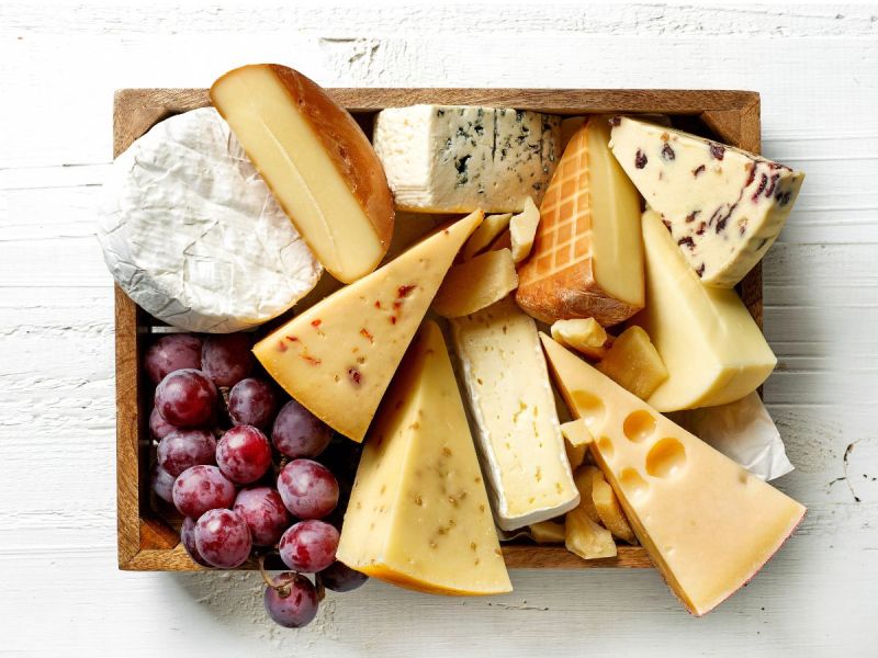 Multiple cheeses on a cheese board with grapes