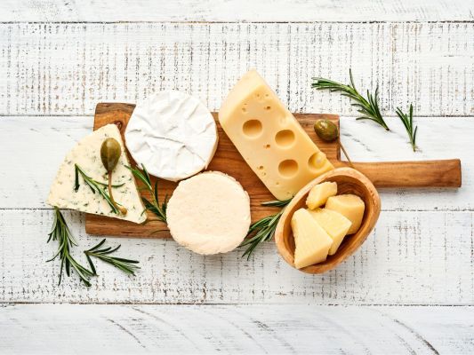 Wooden cheese board with various cheeses on it