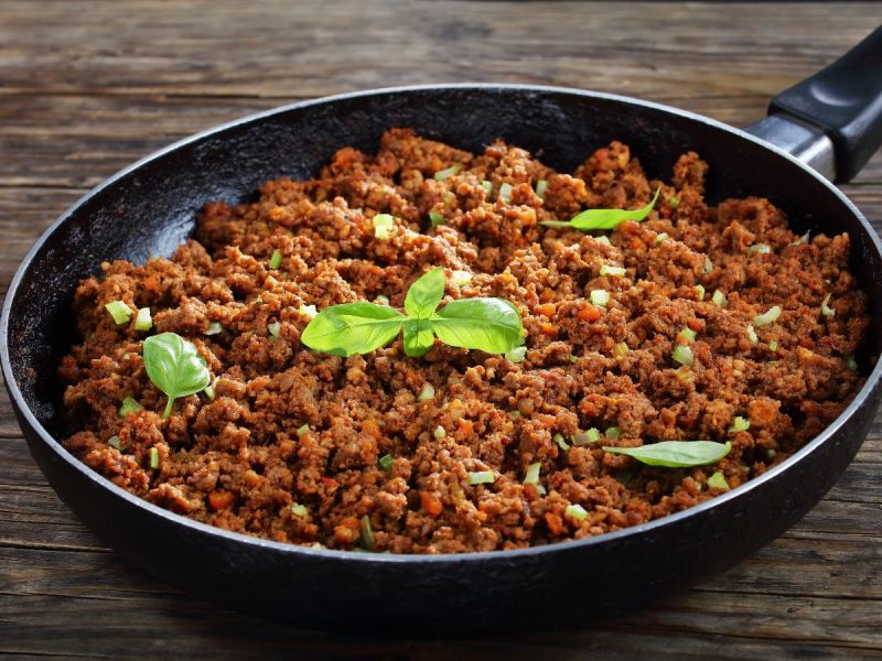 Pan of cooked ground beef sprinkled with herbs