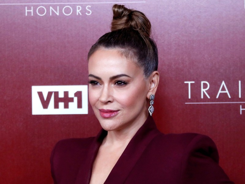 Alyssa Milano poses in burgundy blazer against matching backdrop