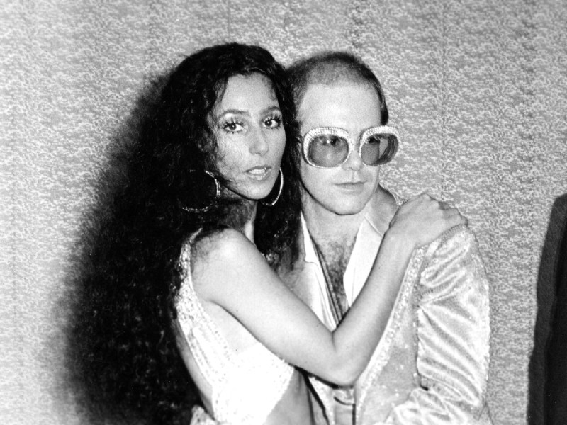 black and white photo of Cher and Elton John hugging circa 1975