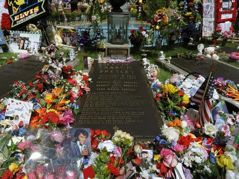 Photo of Elvis Presley's grave with lots of flowers and momentos showered over it