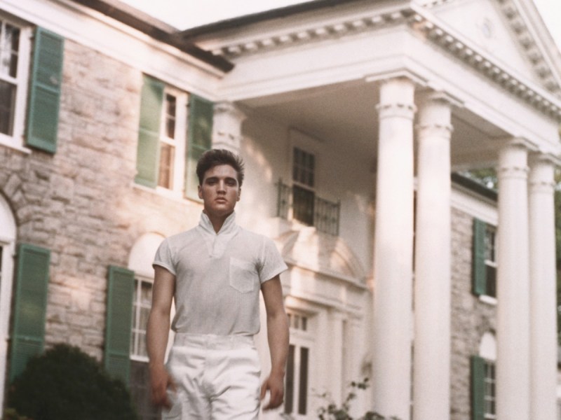 Elvis Presley stands in front of Graceland