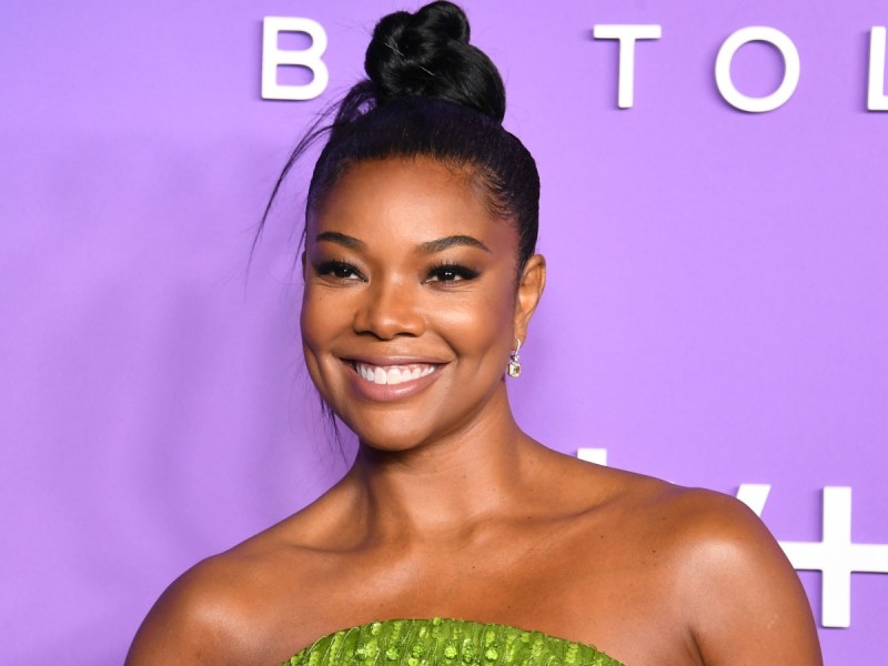 Gabrielle Union smiles in closeup image against purple backdrop