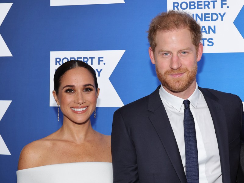 Prince Harry in a blue suit with Meghan Markle in a white dress